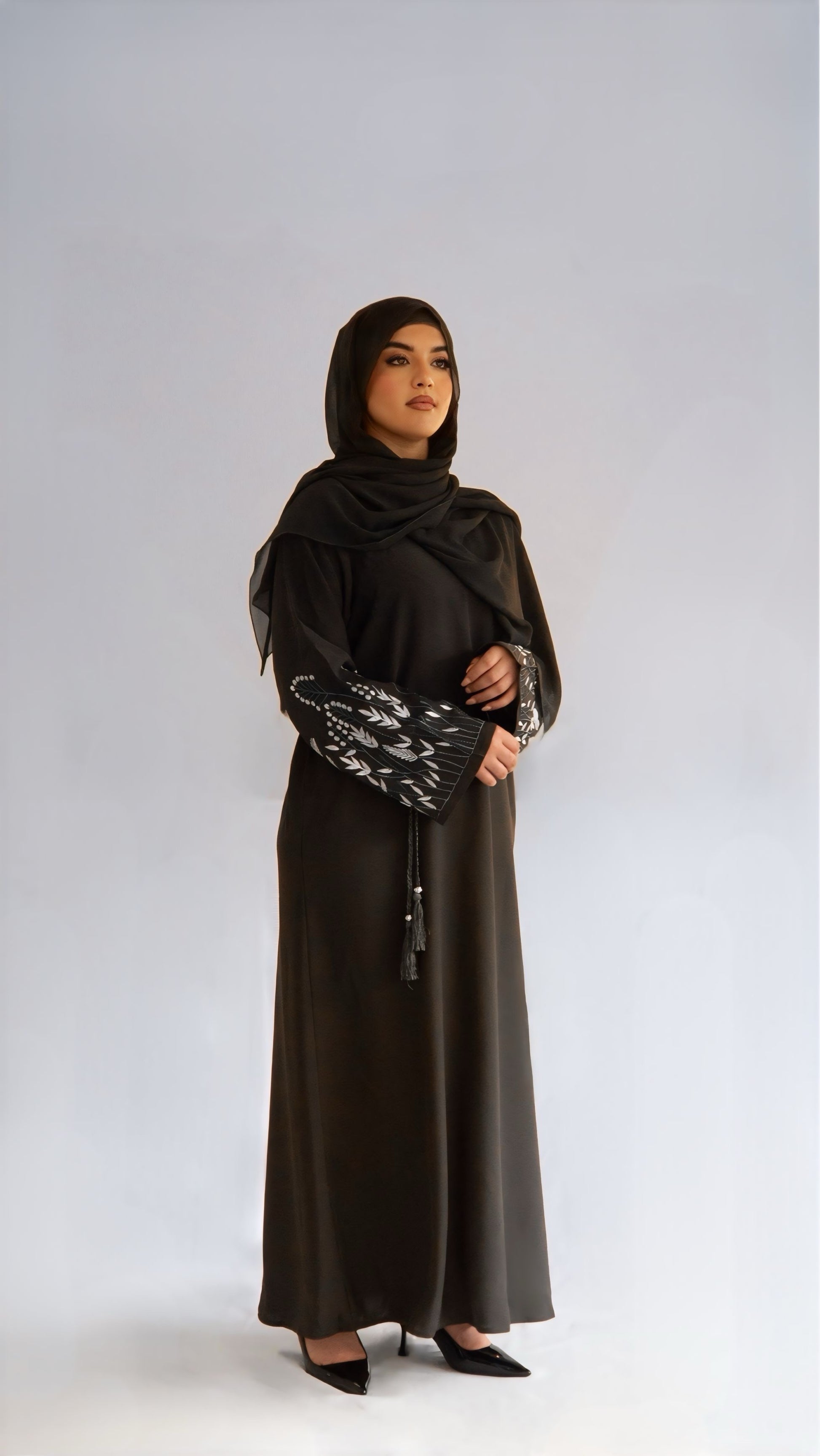 Femme de profil droit portant la abaya Olive Grace, regard à l'horizon